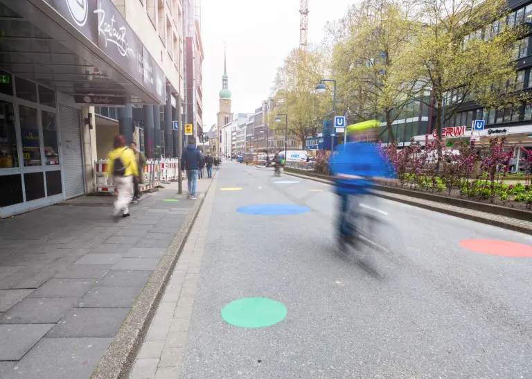 Eine asphaltierte Straße, auf der bunte Kreise angebracht sind. Es handelt sich um die Kampstraße.