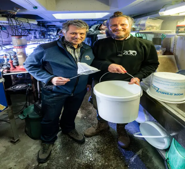 Links Dr. Philipp Wagner, der einen Kescher in der Hand hält, und rechts Marcel Stawinoga, der einen Eimer in den Händen hält.