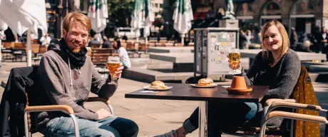 Zwei Personen auf dem Alten Markt trinken Bier