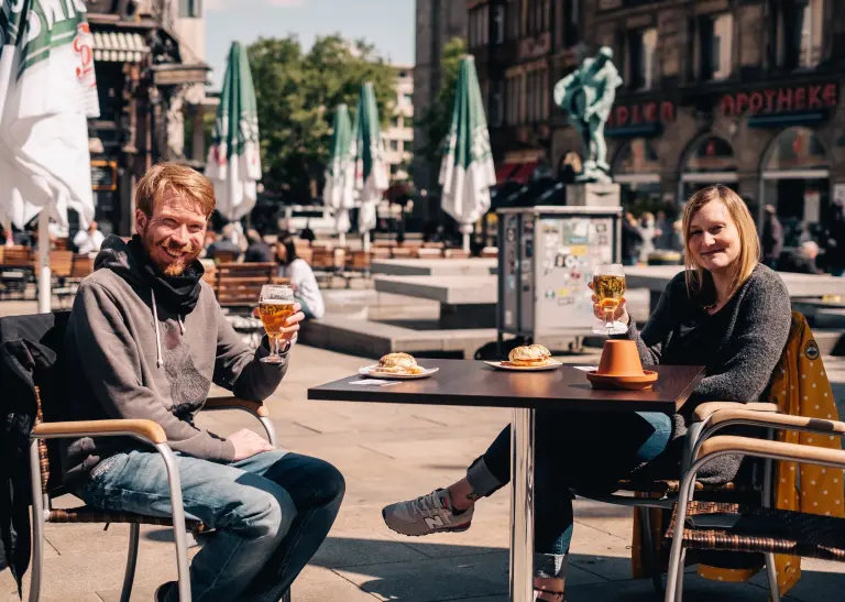 Zwei Personen auf dem Alten Markt trinken Bier