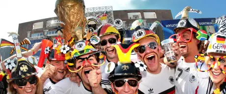 Fußballfans im Deutschland-Trikot und mit schwarz-rot-goldener Bemalung jubeln vor dem Rathaus