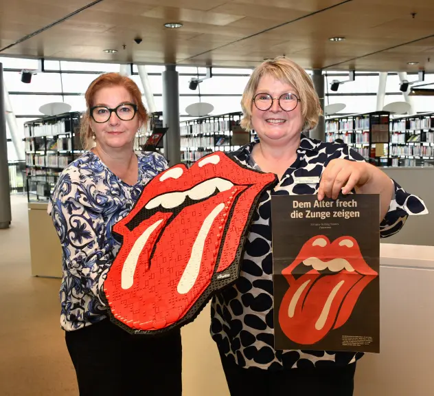 Zwei Bibliotheks-Mitarbeiterinnen präsentieren Rolling-Stones-Zungen