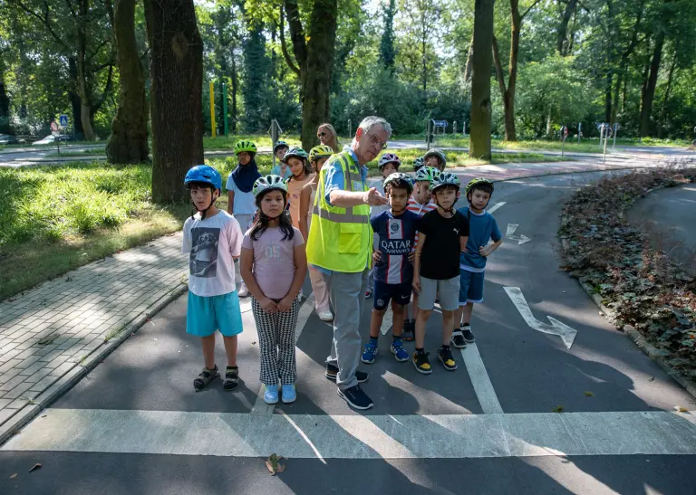 Ein Mann in einer ADFC-Weste erklärt einer Gruppe Kindern etwas