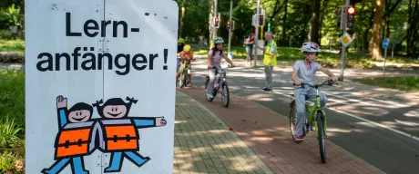 Ein Schild mit der Aufschrift Lernanfänger, im Hintergrund Kinder auf Fahrrädern