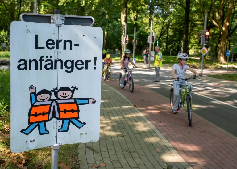 Ein Schild mit der Aufschrift Lernanfänger, im Hintergrund Kinder auf Fahrrädern