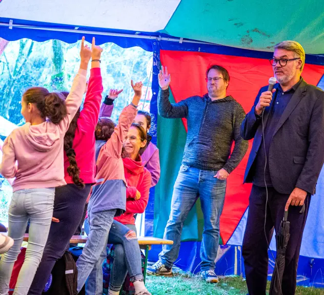 Dortmunds Oberbürgermeister Thomas Westphal spricht stehend in einem bunten Zelt vor Kindern.