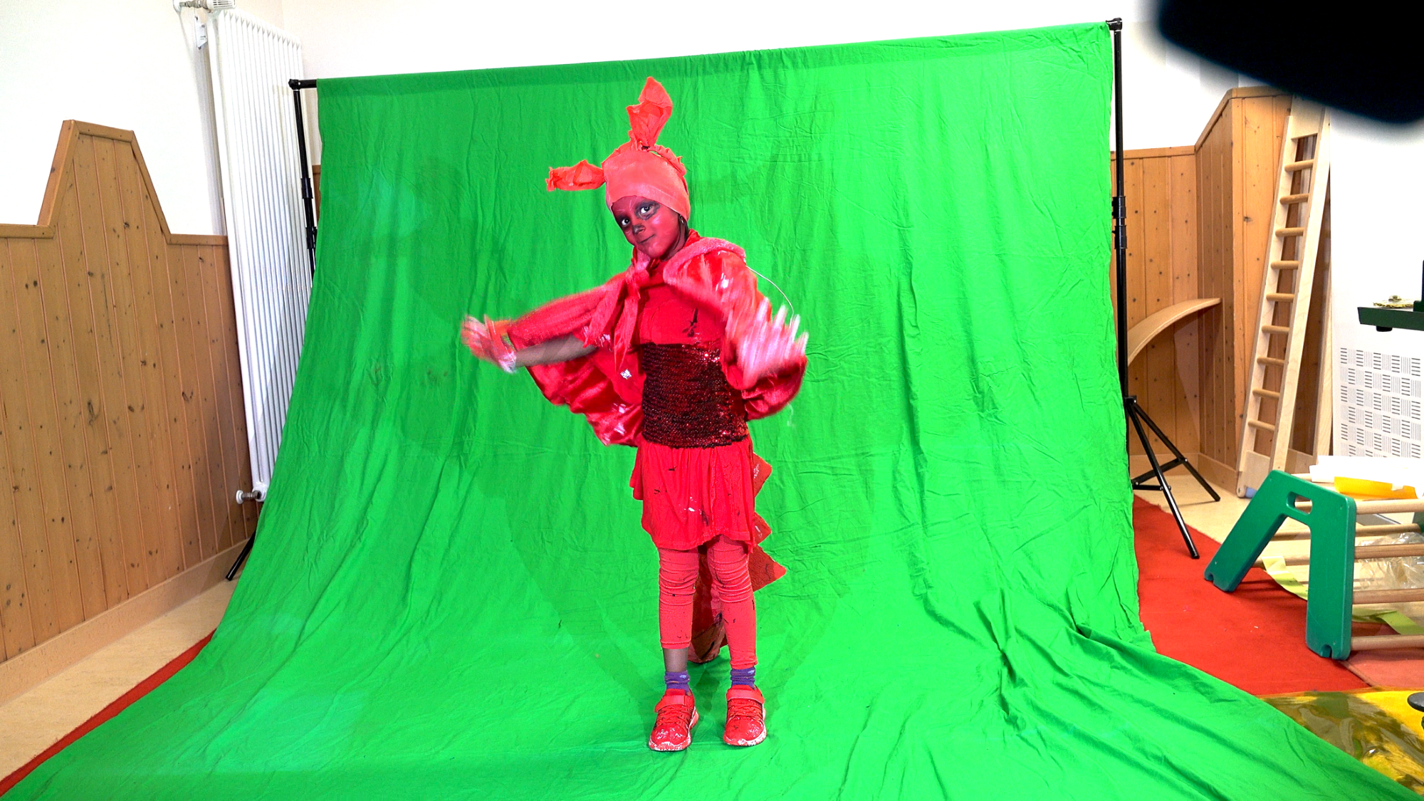 Ein Kind im roten Kostüm schauspielert auf einem Greenscreen