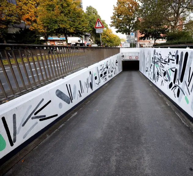 Links und rechts einer Parkhaus-Einfahrt sind Grafittis angebracht.