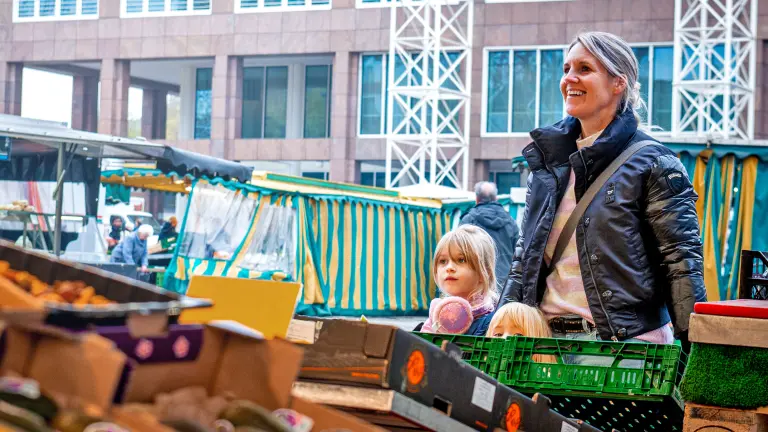 Zwei junge Frauen laufen über den Wochenmarkt auf dem Hansaplatz und essen Trauben