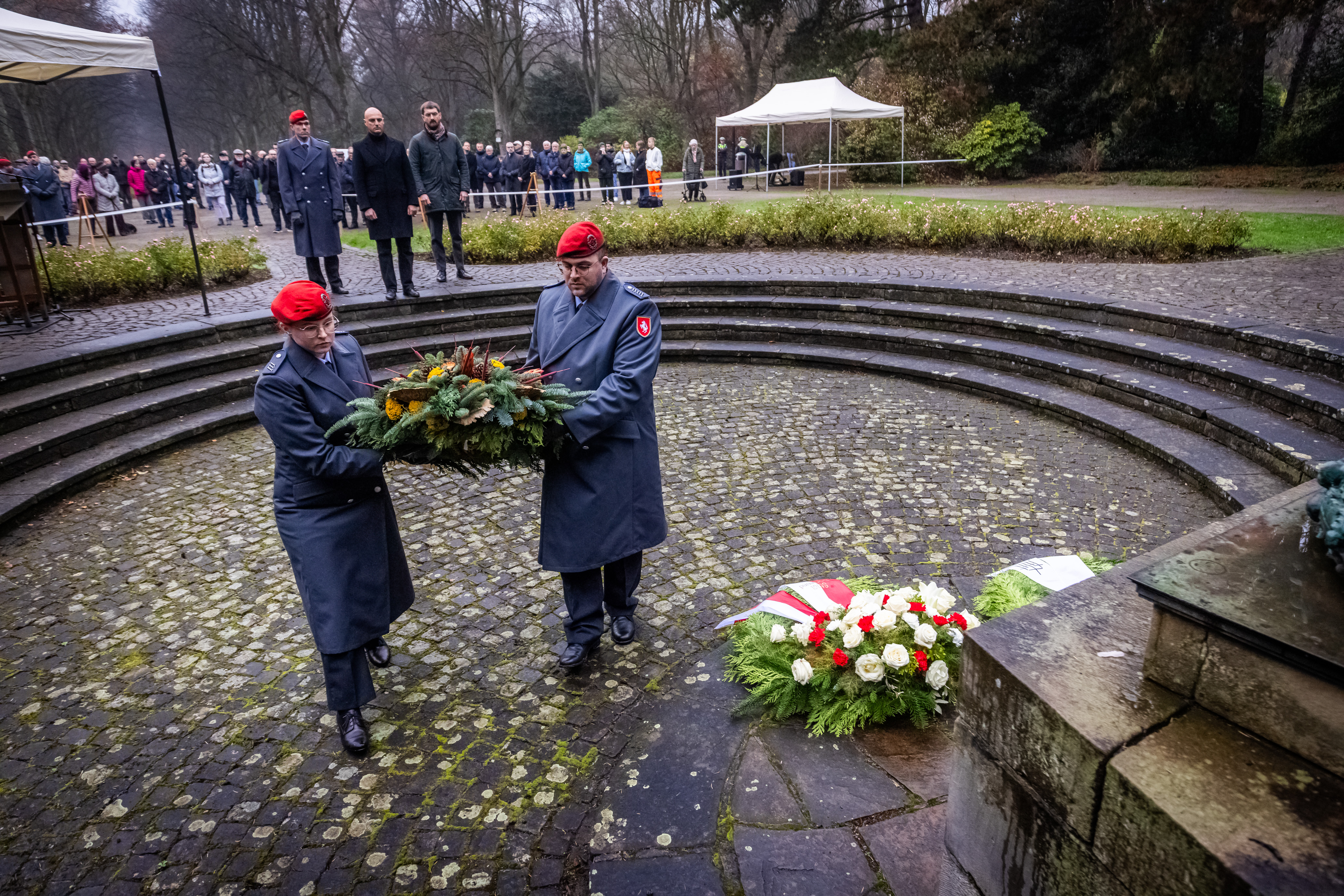 Zwei Vertreter aus der Bundeswehr legen einen Kranz bei der Gedenkfeier zum Volkstrauertag nieder. Im Hintergrund ist auch OB Kalouti.
