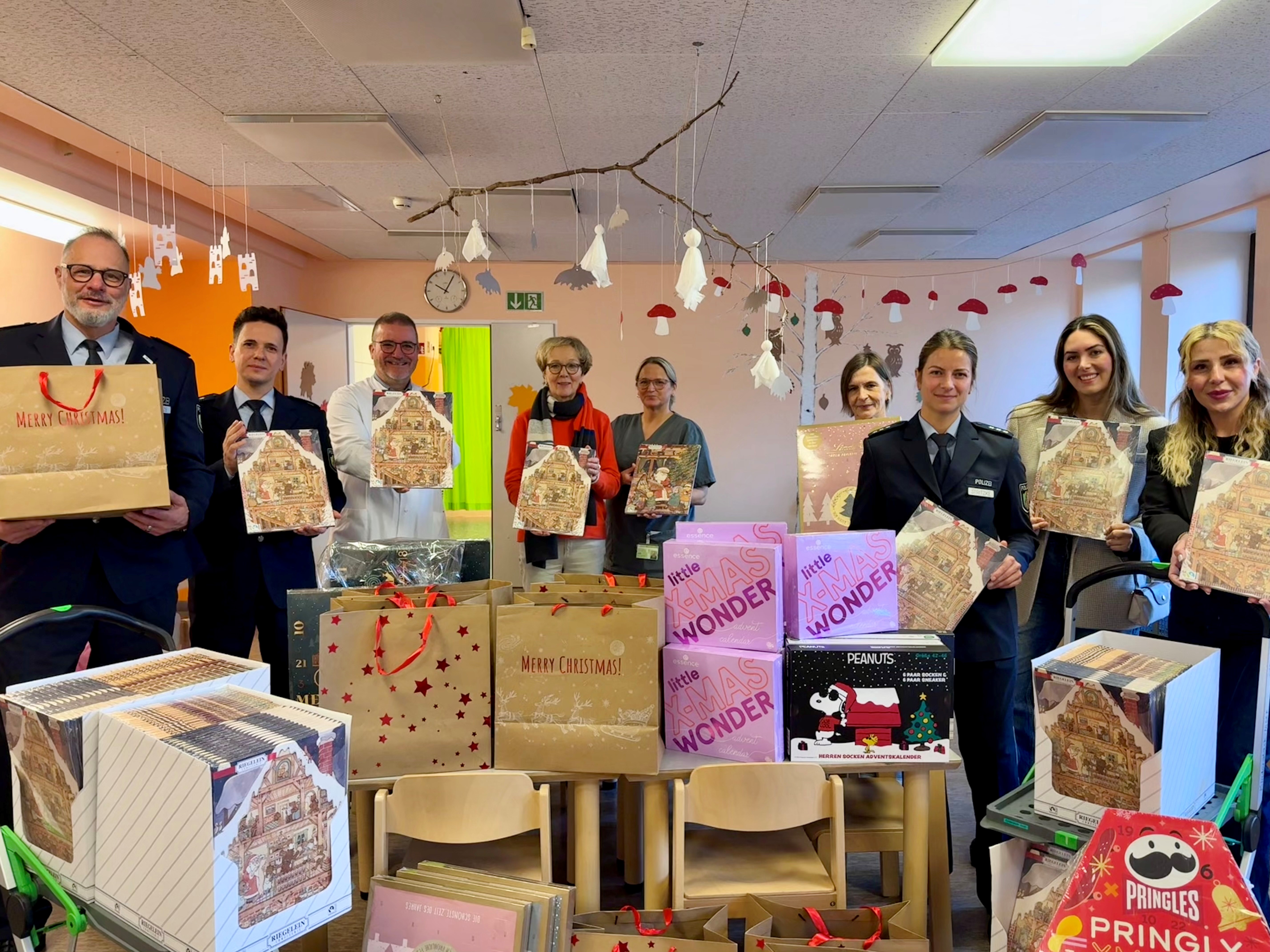 Uniformierte Polizisten und mehrere Personen in Zivil halten Adventskalender in die Kamera, sie stehen im Klinikum Dortmund.