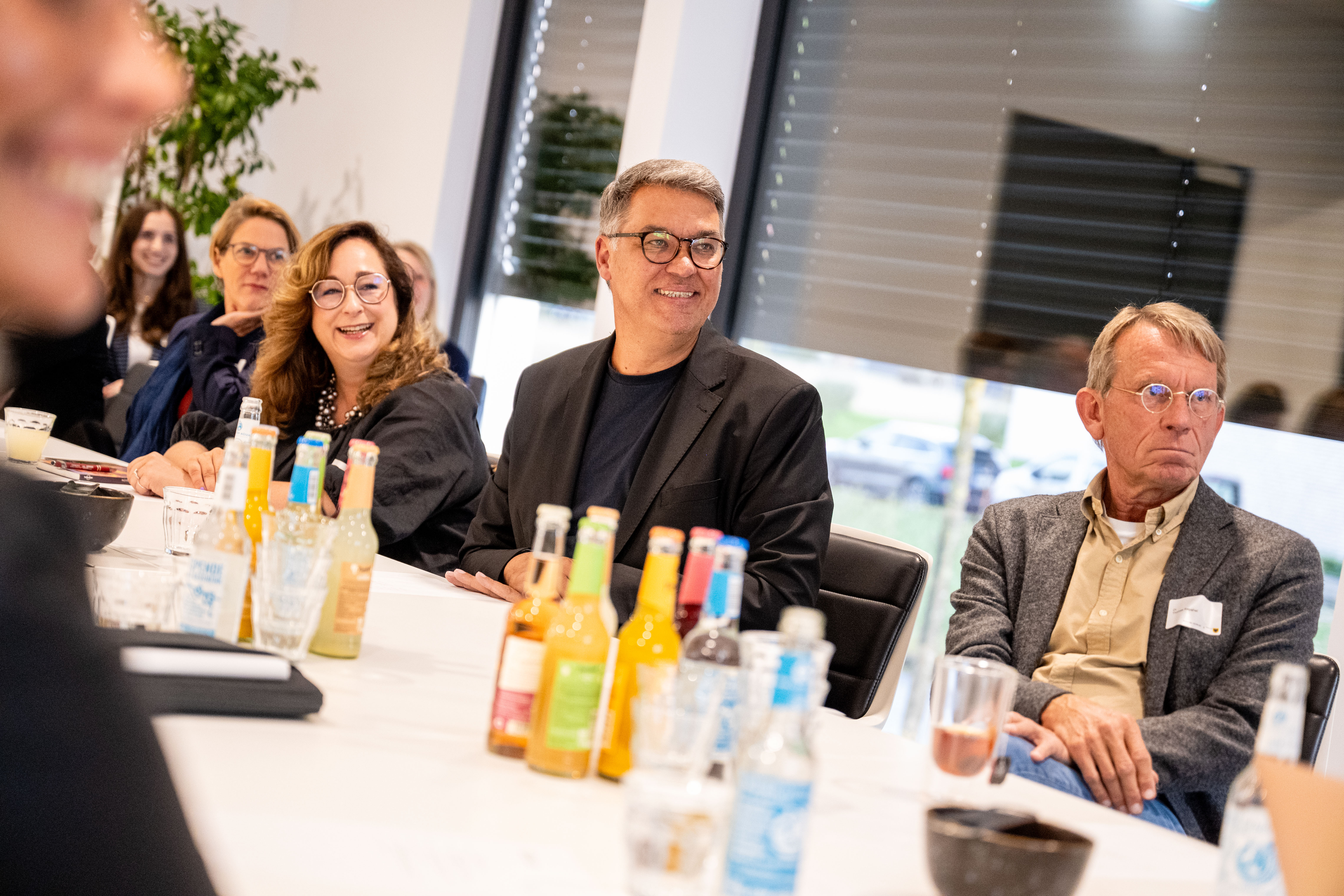 Mehrere Personen sitzen am Tisch und schauen nach rechts. In der Mitte sitzt der Dortmunder Bürgermeister Thomas Westphal.