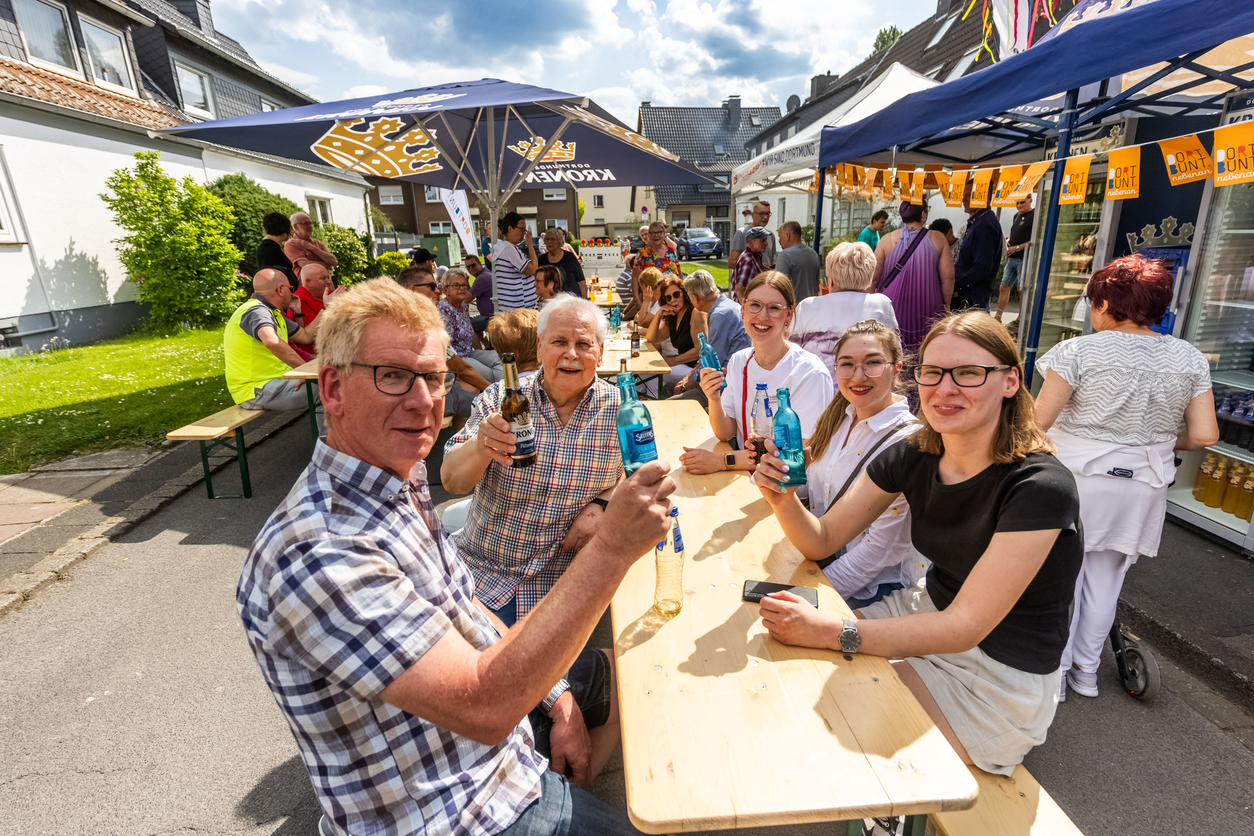 Menschen auf einer Bank mit Getränken beim Nachbarschaftsfest Mengede.