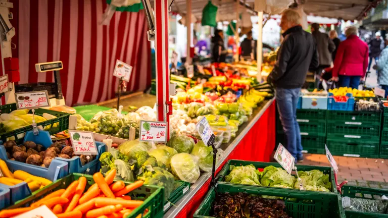 Ein Mann betrachtet einen Gemüsestand auf dem Markt