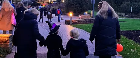 Familien beim Spaziergang durch den Westfalenpark während des Halloween-Festes bei Einbruch der Dämmerung, mit leuchtenden Laternen und kinderfreundlicher Atmosphäre