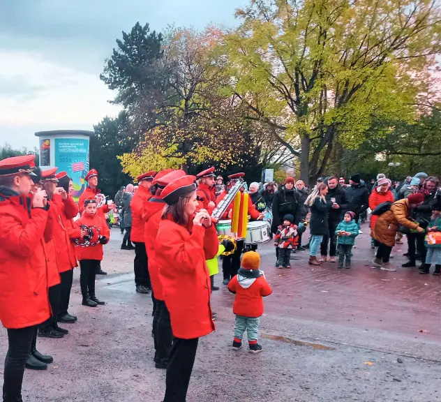 Musikkapelle in roten Jacken spielt während des St. Martins-Zugs im Westfalenpark, umgeben von Familien mit Kindern in herbstlicher Stimmung