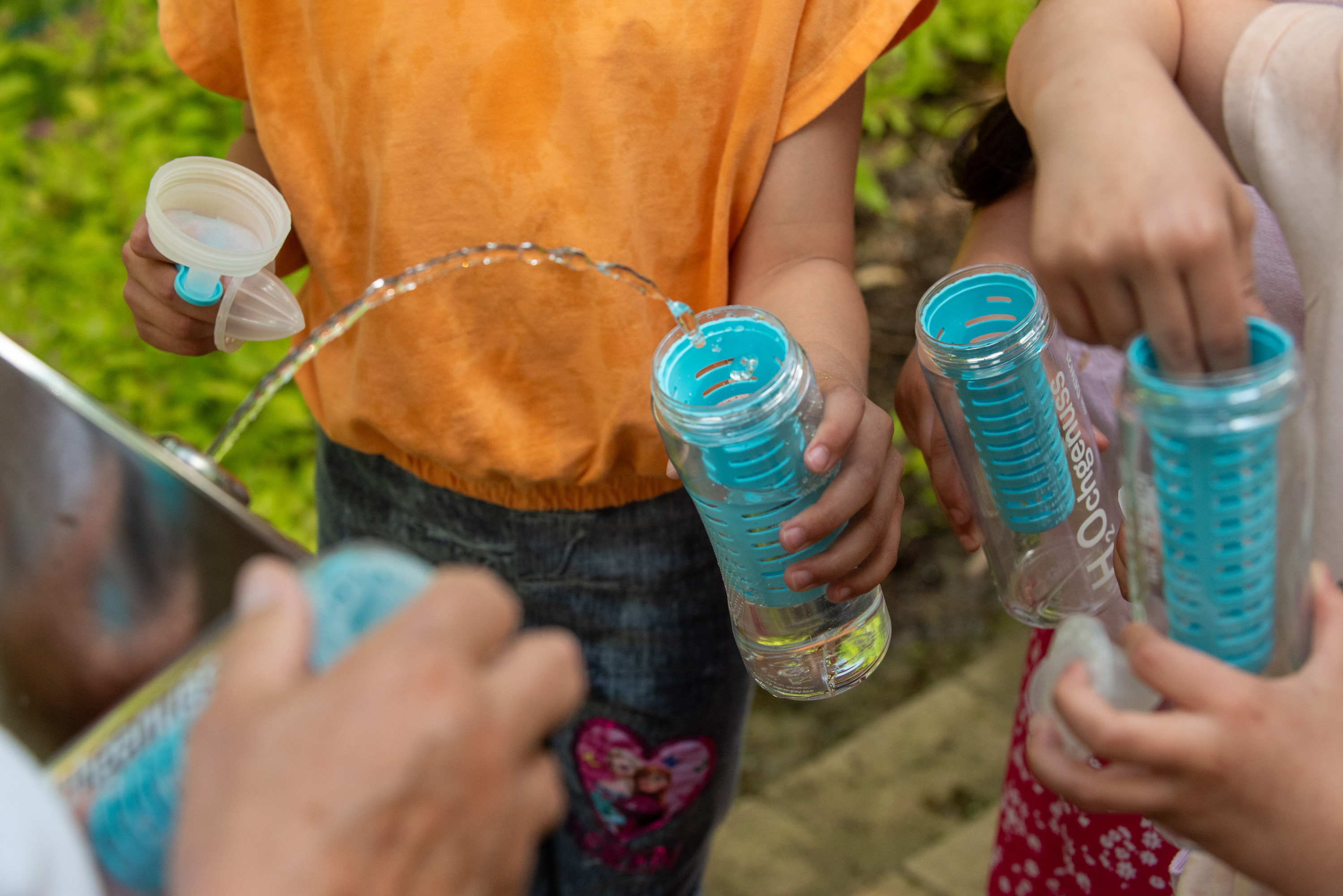 Kinder füllen ihre Flaschen am Trinkwasserbrunnen auf