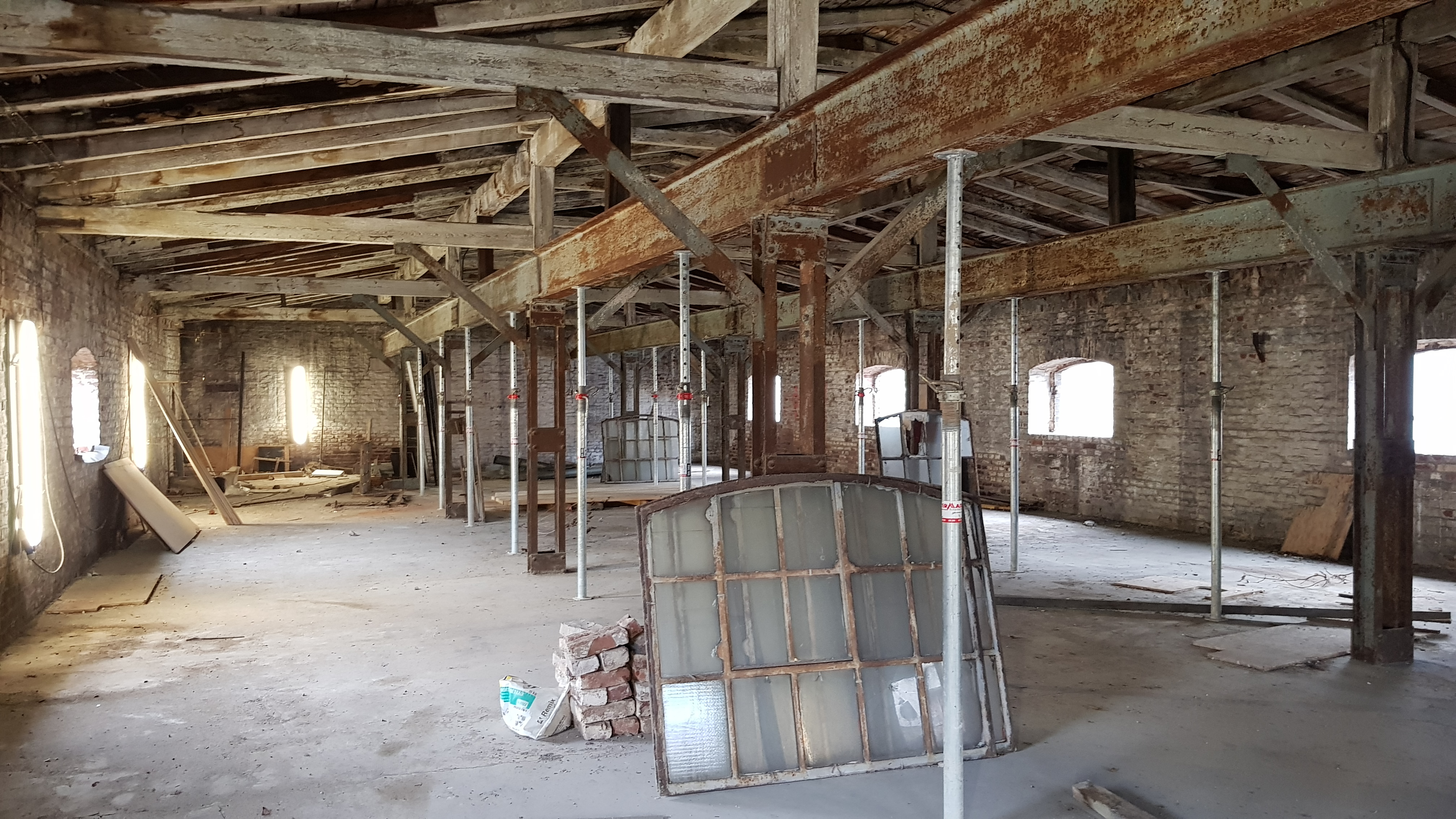 Innenraum eines Backsteingebäudes mit unverputzten Wänden und verwitterten Stahlträgern