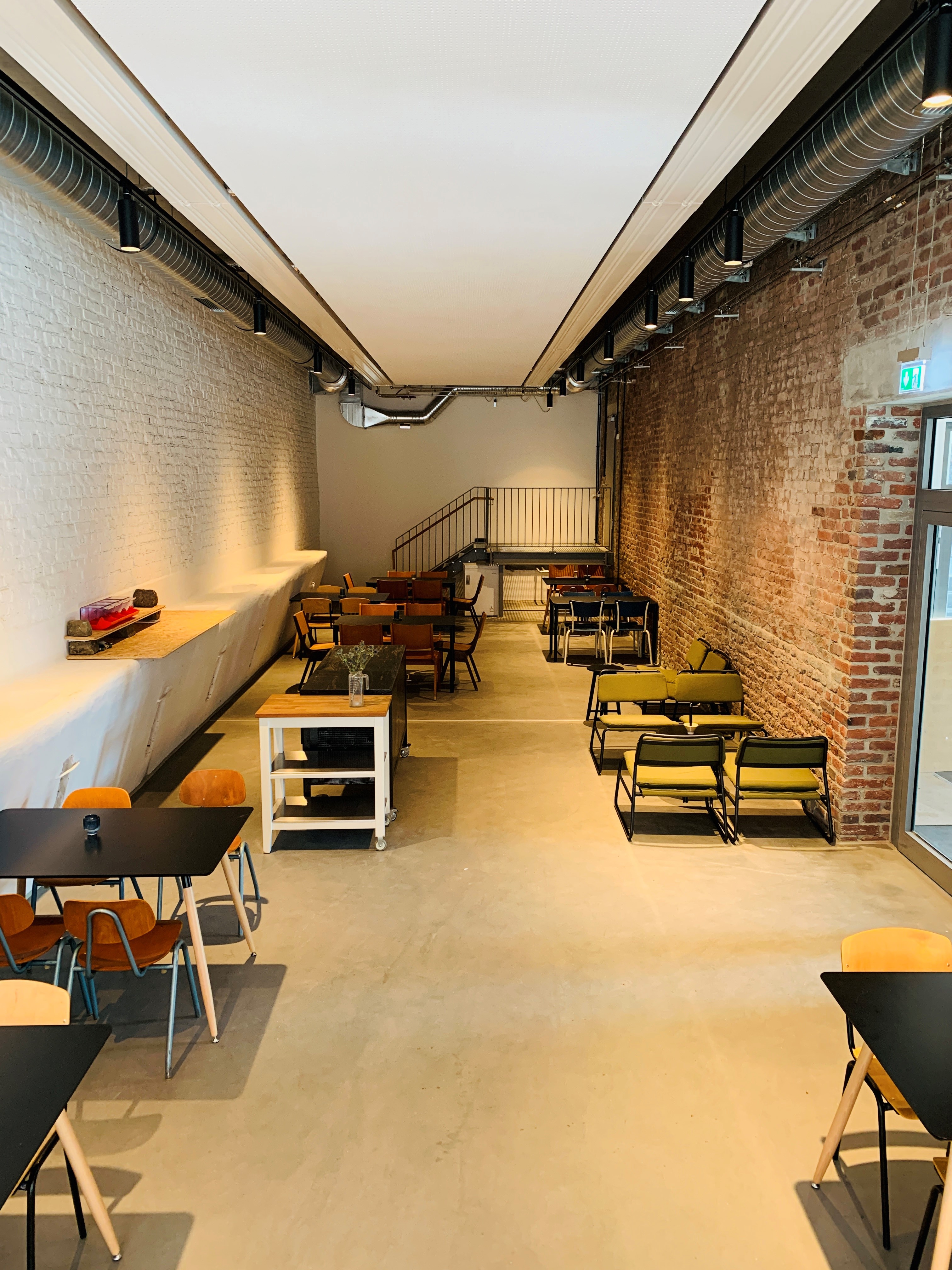 Langgestreckter Raum mit Tischgruppen sichtbarem Mauerwerk.