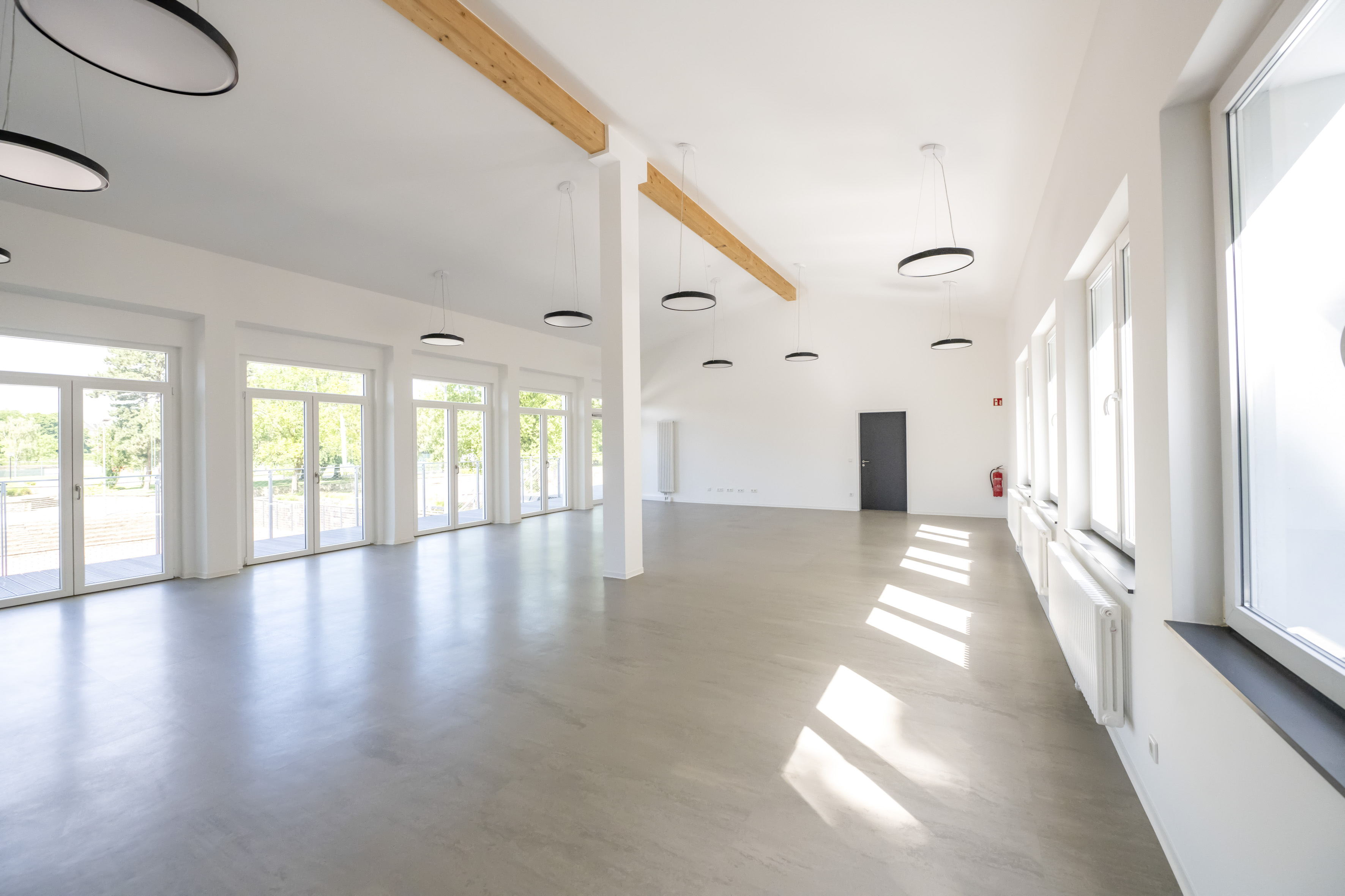 Blick in einen langen, hellen Raum, in den von beiden Seiten Tageslicht fällt. 