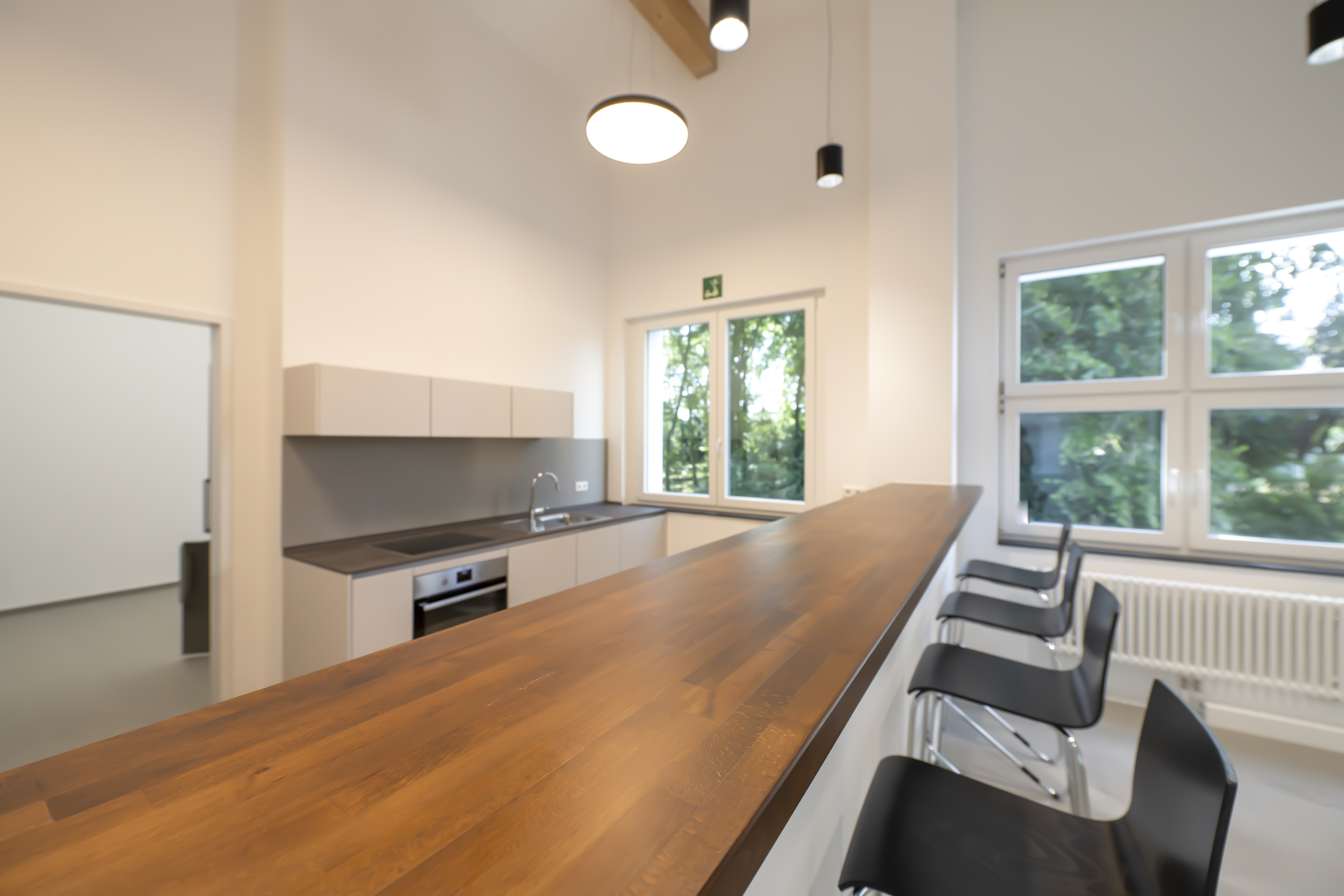 Graue Küchenzeile hinter einem Küchentresen mit Holzoberfläche.