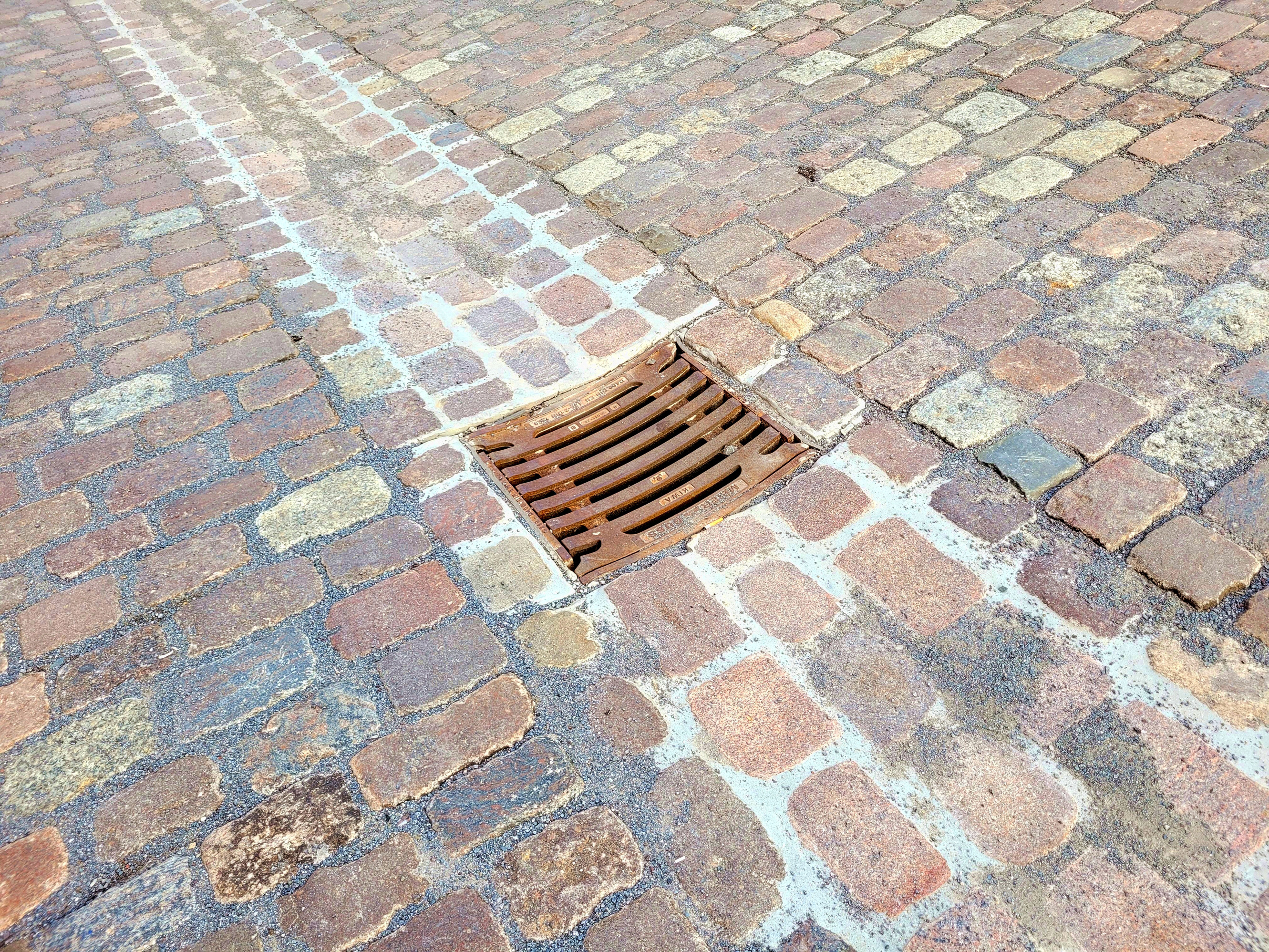 Kopfsteinpflaster mit einem rechteckigen Gullideckel