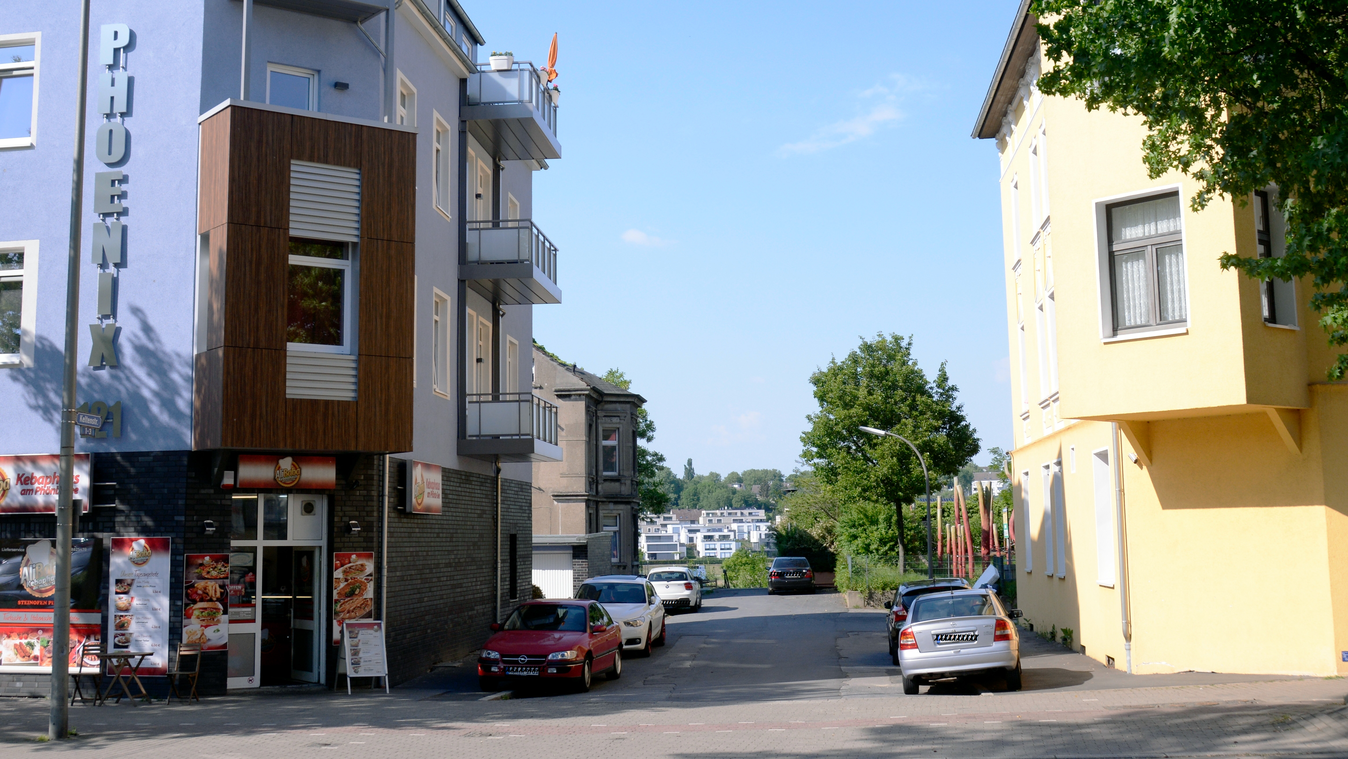 Foto einer Straße, im Hintergrund ein See.