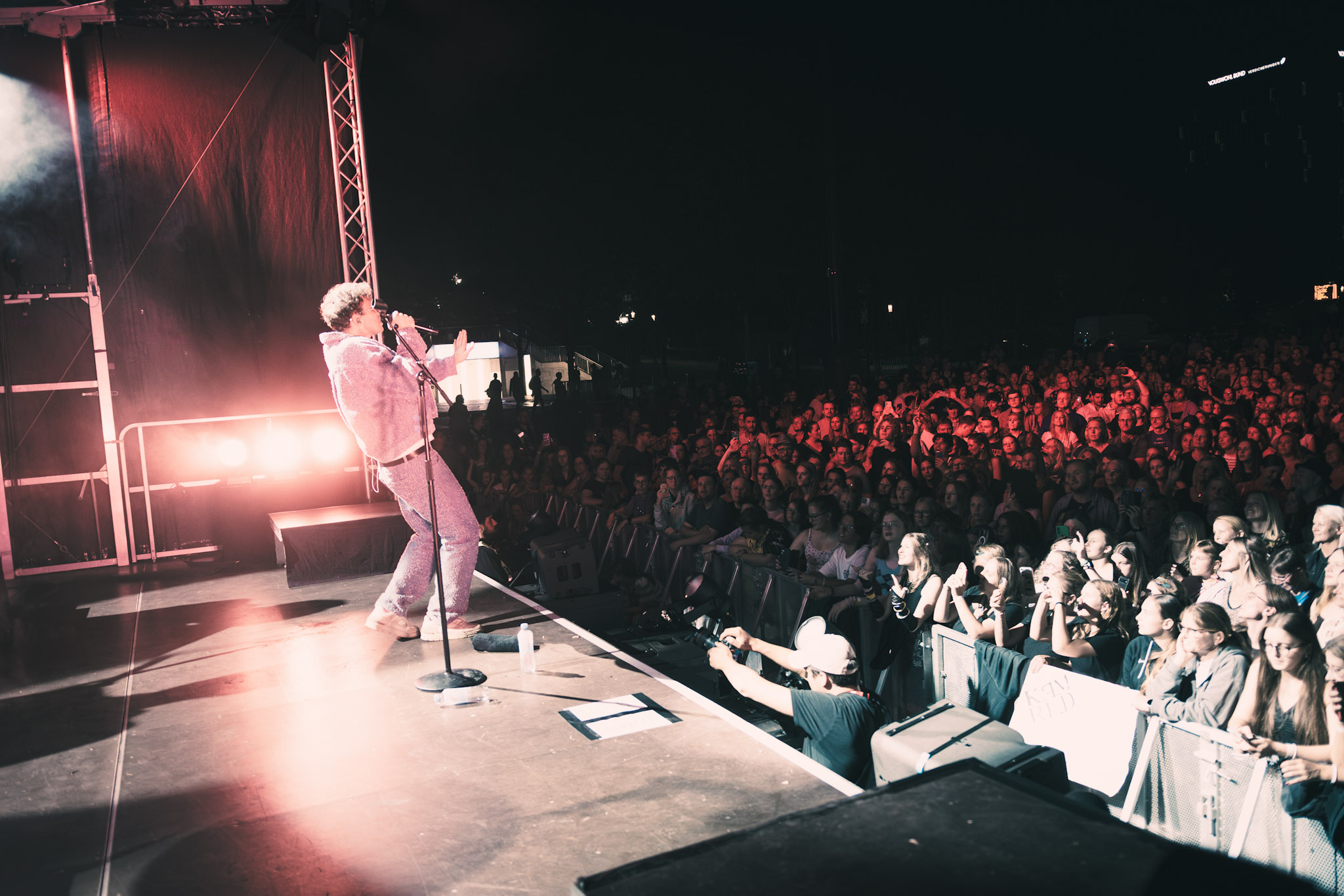 Zu sehen ist der Musiker KAMRAD auf der Bühne. Vor ihm befindet sich der mit Menschen gefüllte Friedensplatz.