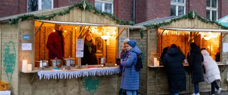 Menschen vor den Holzhütten vom "Winterzauber Borsigplatz" Weihnachtsmarkt