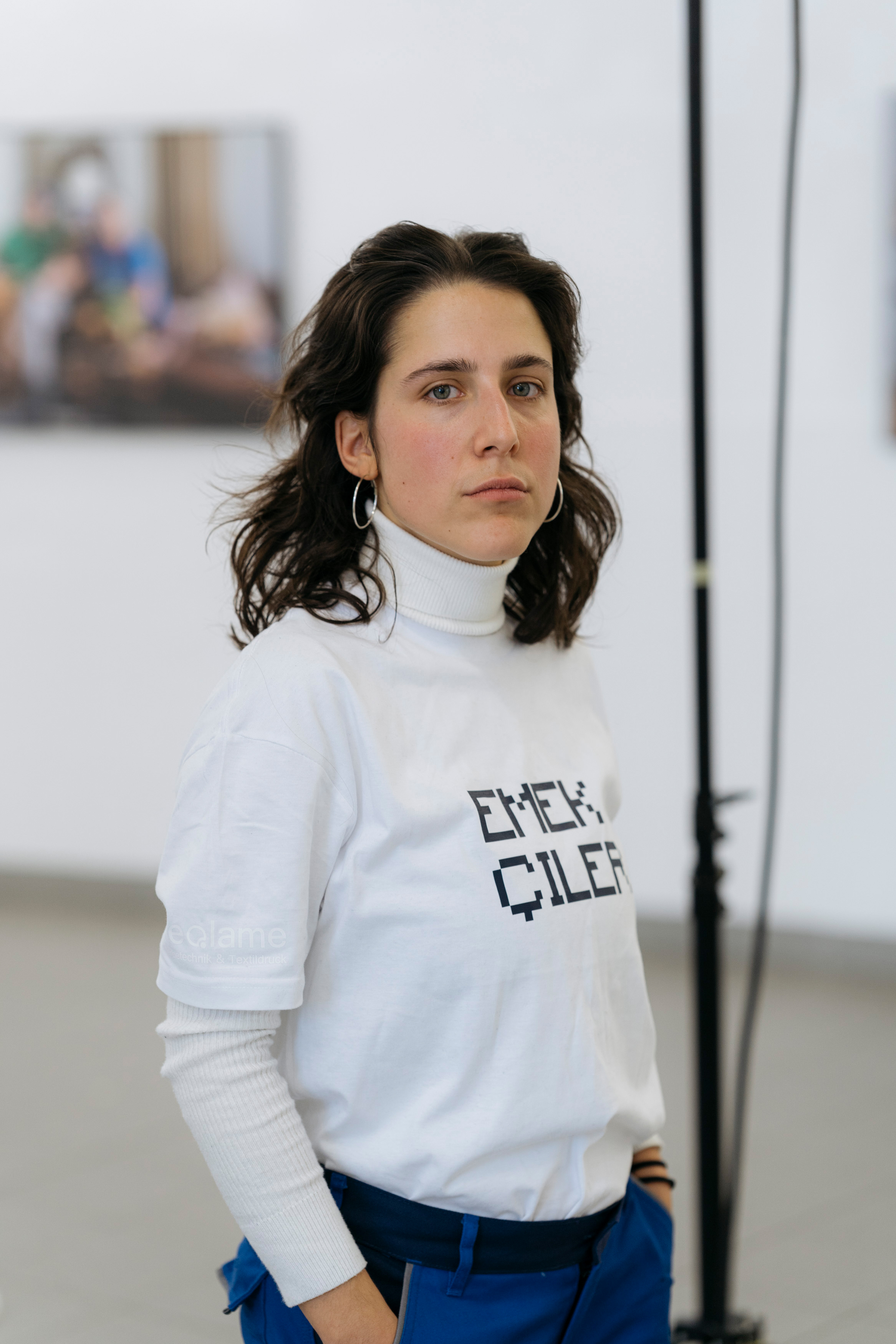 Eine brünette Frau steht seitlich abgewandt und blickt in die Kamera. 