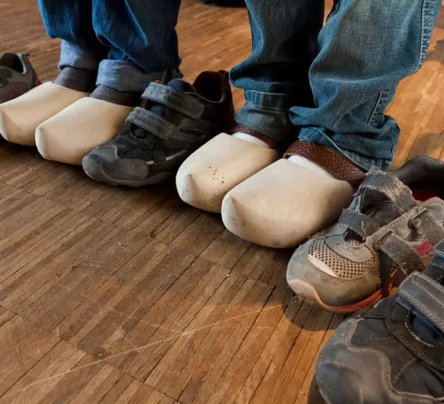 Mehrere Kinderfüße in Holzschuhe stehen nebeneinander